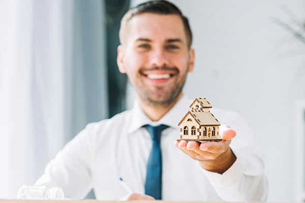 A man is holding a toy house on his hand